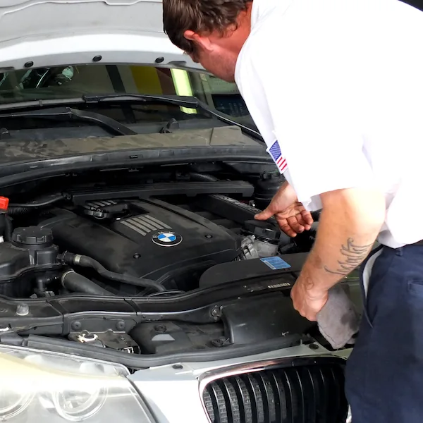 Technician changing fluids in car at oil change shop